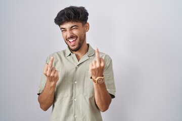Arab man with beard standing over white background showing middle finger doing fuck you bad...