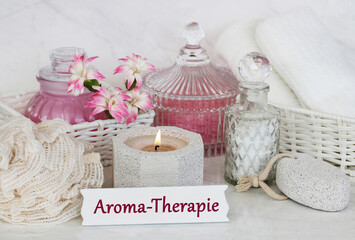 Spa Komposition mit Massageöl, Kerzen und dem Text Aroma-Therapie.