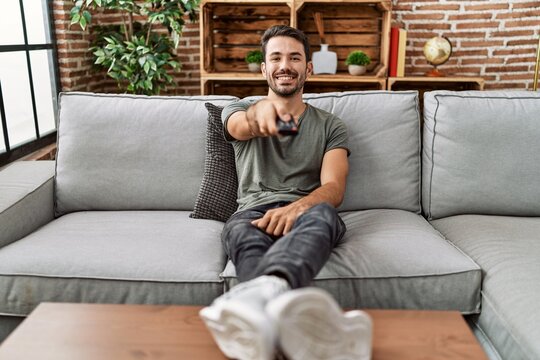 Young hispanic man smiling confident watching tv at home