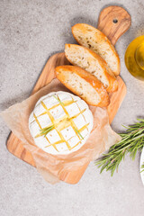 Baked camembert soft cheese. Grilled brie with toasts and rosemary. 