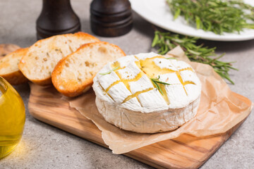 Baked camembert soft cheese. Grilled brie with toasts and rosemary. 