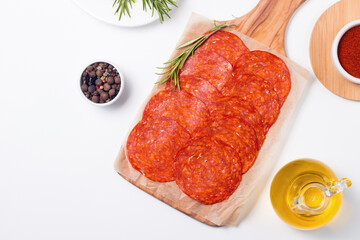 Chorizo sausage and salami, thin cut. Spanish salami on the wood background with spices, paprika, rosemary and olives. Spicy food. Antipasto and appetizer meat. 