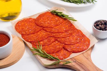 Chorizo sausage and salami, thin cut. Spanish salami on the wood background with spices, paprika, rosemary and olives. Spicy food. Antipasto and appetizer meat. 