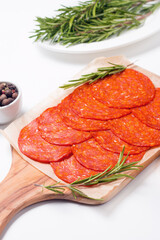 Chorizo sausage and salami, thin cut. Spanish salami on the wood background with spices, paprika, rosemary and olives. Spicy food. Antipasto and appetizer meat. 