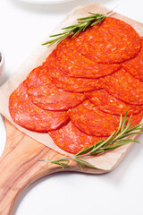 Chorizo sausage and salami, thin cut. Spanish salami on the wood background with spices, paprika, rosemary and olives. Spicy food. Antipasto and appetizer meat. 