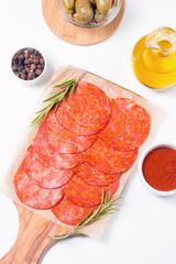 Chorizo sausage and salami, thin cut. Spanish salami on the wood background with spices, paprika, rosemary and olives. Spicy food. Antipasto and appetizer meat. 