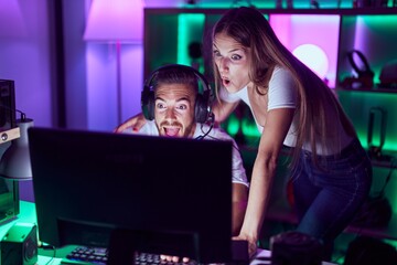 Young couple playing video games celebrating crazy and amazed for success with open eyes screaming...