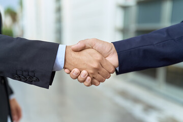 Two hispanic men business workers shake hands at street