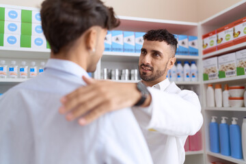 Two hispanic men pharmacist speaking to client at pharmacy