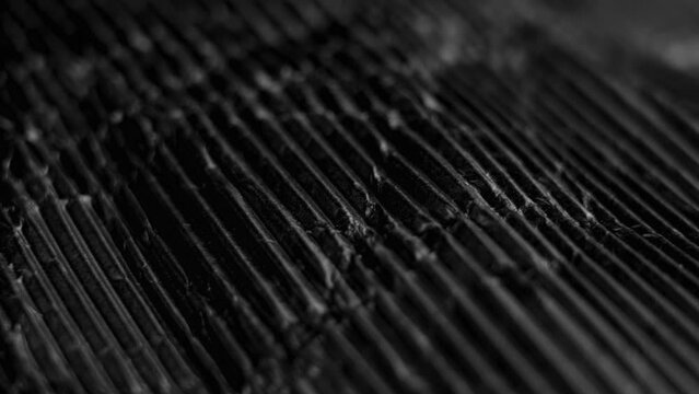 Black paper textured abstract background with crumples and wrinkles. Grooved cardboard background. Macro. Rotation