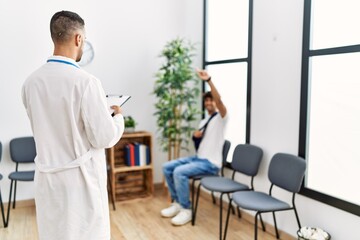 Two hispanic men doctor and patient at hospital waiting room