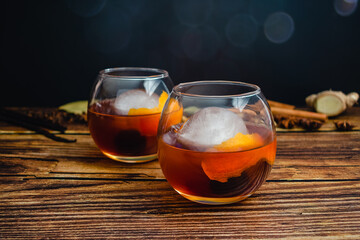 Spiced Old Fashioned Cocktail in a Balloon Glass With an Ice Sphere: Bourbon whiskey cocktail with an orange peel and maraschino cherry garnish