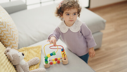 Adorable hispanic girl playing with toy standing at home