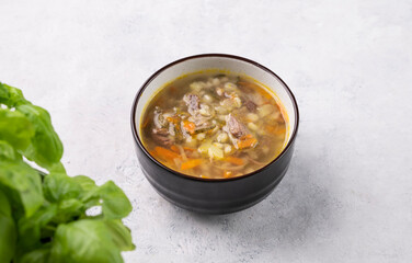 Traditional Russian soup with pickled cucumbers. Pickle with pearl barley and meat on a light background with fresh herb.