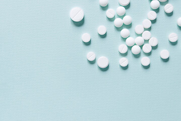 Scattered white pills on blue table. Mock up for special offers as advertising, web background or other ideas. Medical, pharmacy and healthcare concept. Copy space. Empty place for text or logo
