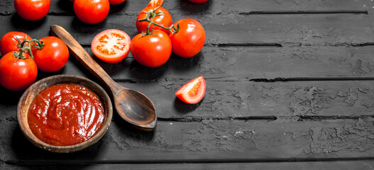 Fototapeta na wymiar Tomato sauce in bowl with spoon and slices of ripe tomatoes.