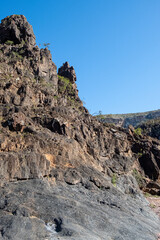 Sunlit cliff with view and brown rocks