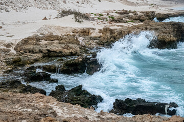 Waves crashing at rocky beach with sand