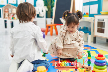 Two kids playing xylophone sitting on floor at kindergarten