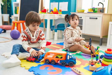 Fototapeta premium Two kids playing with cars toy sitting on floor at kindergarten