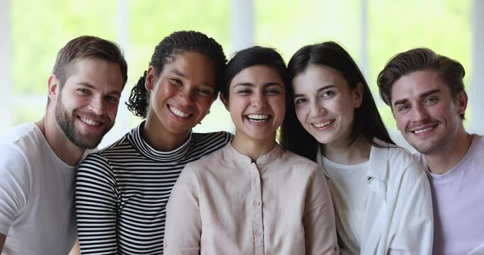 Group of happy pretty multi ethnic girls and guys pose smile look at camera, laughing, gathered together hanging out, enjoy communication. Strong friendship or multiracial young people students, amity