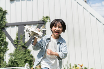 Asian boy playing with toy airplane outdoor. Kid having fun with toy airplane in the garden © amorn