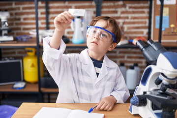 Adorable hispanic boy student smiling confident looking sample at laboratory classroom