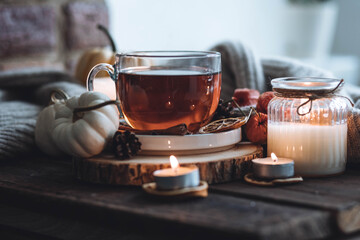 Autumn cozy home composition with hot herbal tea and candles. Aromatherapy on a grey fall morning, atmosphere of cosiness and relax. Wooden background, window sill, close up.
