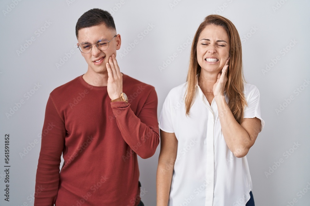 Sticker mother and son standing together over isolated background touching mouth with hand with painful expr