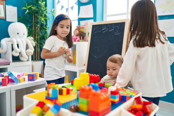 Group of kids playing with construction blocks standing at kindergarten