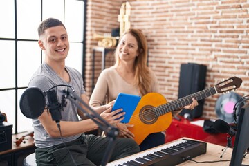 Fototapeta na wymiar Man and woman musicians having classic guitar lesson using touchpad at music studio