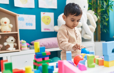 Adorable hispanic toddler playing with construction blocks standing at home