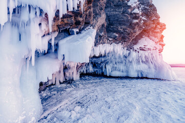 Blue Ice cave or grotto on winter lake Baikal. Beautiful winter landscape with long icicles