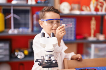 Adorable hispanic toddler student smiling confident looking sample at classroom