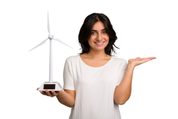 Young Indian woman holding a small wind energy mill isolated showing a copy space on a palm and holding another hand on waist.