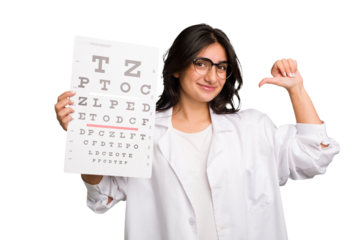 Young indian oculist woman holding an eye chart paper cut out isolated feels proud and self confident, example to follow.