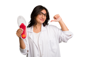 Young indian chiropodist woman holding a insoles for shoes cut out isolated feels proud and self confident, example to follow.