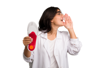Young indian chiropodist woman holding a insoles for shoes cut out isolated shouting and holding palm near opened mouth.