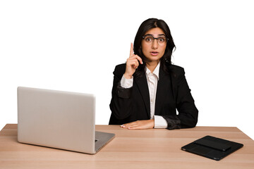 Young indian woman in a table with a laptop and tablet isolated having an idea, inspiration concept.