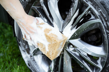 car wash, car care, summer car wash. Cleaning the car with water, washing alloy wheels