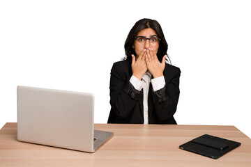 Young indian woman in a table with a laptop and tablet isolated shocked, covering mouth with hands, anxious to discover something new.