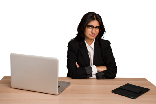 Young indian woman in a table with a laptop and tablet isolated unhappy looking in camera with sarcastic expression.
