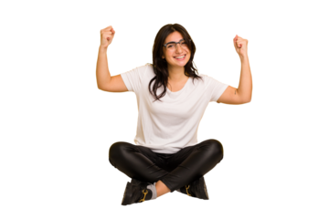 Young indian woman sitting on the floor cut out isolated showing strength gesture with arms, symbol of feminine power