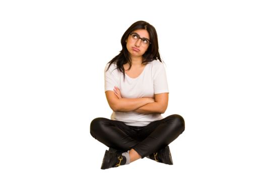 Young indian woman sitting on the floor cut out isolated tired of a repetitive task.