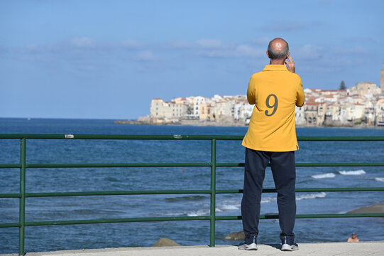 Senior mit gelbem Hemd blickt auf die Bucht von Cefalu auf Sizilien