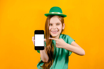 Black smartphone with a white screen in the hands of a baby girl on St. Patrick's Day. Advertising, sale concept.