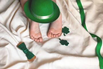 Children's feet and heels on a white bed to Saint Patrick's Day. Infant baby is sleeping in his crib. Importance of sleep for babies. Sleep mode babies 3 y.o.