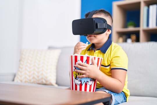 Adorable hispanic boy watching 3d movie sititng on sofa at home