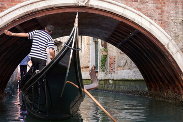 Fototapeta na wymiar MAY 20, 2017 - VENICE, ITALY: Gondola going under old bridge on canal in Venice. View from gondola.