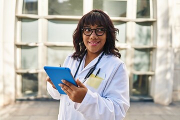 Young beautiful latin woman doctor smiling confident using touchpad at hospital